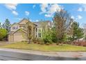 Beautifully landscaped front yard with mature trees surrounding a beige home and three-car garage at 5791 Chisholm Pl, Parker, CO 80134