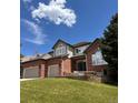 Charming two-story brick home with a landscaped lawn, attached garage, and a welcoming front entrance at 6577 Esperanza Dr, Castle Pines, CO 80108