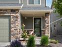 Charming front porch area with a stone-accented facade, a green front door, and beautiful landscaping at 5358 Ventura St, Denver, CO 80249