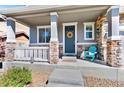 Inviting front porch with stone pillars, a cozy seating area, and a decorative wreath on the door at 20529 E Brunswick Pl, Aurora, CO 80013