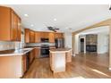 Spacious kitchen with wood cabinets, center island, stainless steel appliances, and adjacent fireplace at 16351 E 104Th Pl, Commerce City, CO 80022