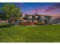 Exterior shot of the house with green grass and a big tree on a beautiful sky at dusk at 6962 W 87Th Way # 270, Arvada, CO 80003