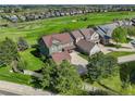 Aerial view of a two-story home with an attached garage, green lawn, and golf course views at 23427 Song Bird Hills Pl, Parker, CO 80138