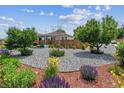 Landscaped front yard with decorative rock, mulch beds, flowering plants, and mature trees at 2196 W 56Th Ave, Denver, CO 80221