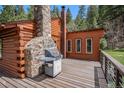 Outdoor stone fireplace and grill on wooden deck, perfect for outdoor cooking and entertaining at 11080 S Deer Creek Rd, Littleton, CO 80127