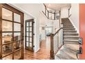 Elegant foyer showcasing hardwood floors, an open staircase, and glass French doors to the left at 1157 Mircos St, Erie, CO 80516