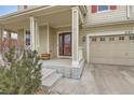 Inviting front porch with classic columns and a view of the two car garage at 1157 Mircos St, Erie, CO 80516