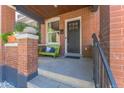 Inviting front porch features a charming green bench, brick pillars, and a well-maintained entryway at 3329 N High St, Denver, CO 80205
