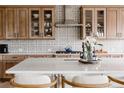 Close-up view of a kitchen showcasing wood cabinets, patterned backsplash, stainless steel hood, and a white countertop island at 27608 E Ottawa Ave, Aurora, CO 80016