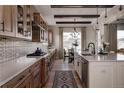 Spacious kitchen features a long island, wood cabinets, patterned backsplash, stainless steel appliances, and hardwood floors at 27608 E Ottawa Ave, Aurora, CO 80016