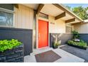 Inviting entrance featuring a bright orange door, dark brick accents, and manicured landscaping around the entryway at 4920 E Vassar Ln, Denver, CO 80222