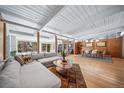 Spacious living room featuring expansive windows, wood-paneled wall, light wood flooring, and an open floor plan at 4920 E Vassar Ln, Denver, CO 80222