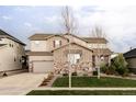 Two-story home with a neutral color scheme, attached two-car garage, manicured lawn, and a mix of stone and siding at 27500 E Lakeview Dr, Aurora, CO 80016