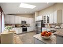 Bright eat-in kitchen featuring skylight, granite countertops, stainless steel appliances, and white cabinetry at 6480 Moss Cir, Arvada, CO 80007