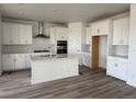 Bright kitchen with white cabinets, stainless steel appliances, an island and wood flooring at 8840 Whiteclover St, Littleton, CO 80125