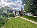 A single-story home with white exterior, brick chimney, and well-kept front lawn at 291 Magnolia St, Denver, CO 80220