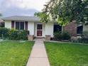 Close-up of a single-story home featuring a brick accent wall, red door, and green lawn at 291 Magnolia St, Denver, CO 80220