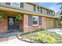 Close up of the beautiful home exterior featuring red brick, a dark double door, and colorful flower beds at 7376 S Jackson St, Centennial, CO 80122