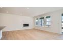 Bright living room with modern fireplace, hardwood floors, and large windows at 605 Twilight St, Erie, CO 80516