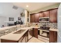 Modern kitchen with stainless steel appliances, dark wood cabinetry, and mosaic tile backsplash at 7409 S Alkire St # 304, Littleton, CO 80127
