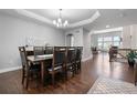 Elegant dining room featuring modern chandelier, tray ceiling, and dark hardwood flooring throughout at 9060 Ferncrest St, Firestone, CO 80504