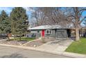 Charming gray home featuring a red front door, attached garage, mature trees, and a well-maintained front lawn at 9639 W 63Rd Pl, Arvada, CO 80004