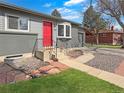 Charming gray home with a bright red front door, complemented by manicured landscaping and a welcoming walkway at 9639 W 63Rd Pl, Arvada, CO 80004