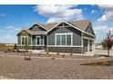 Charming gray home with white trim, stone accents, rock landscaping, and a three-car garage at 9915 E 162Nd Pl, Brighton, CO 80602
