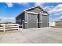 Spacious four-car garage with gray siding, stone accents, and a concrete driveway at 9915 E 162Nd Pl, Brighton, CO 80602