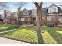 Charming townhome with red brick exterior, manicured lawn and mature trees at 443 Garfield St, Denver, CO 80206