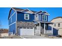 Charming two-story home with blue siding, stone accents, a two-car garage and covered front porch at 758 N Clubview St, Watkins, CO 80137