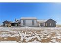 Expansive home with a light stone facade, dark trim, and large windows nestled in a snowy, open landscape at 28450 E 159Th Ave, Brighton, CO 80603