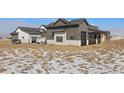 Stunning home exterior boasts stone accents, large windows, and a modern design against a snowy landscape at 28450 E 159Th Ave, Brighton, CO 80603