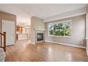 Open-concept living room with wood floors, fireplace, and large window at 12921 Grant Cir # B, Thornton, CO 80241