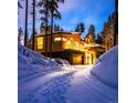 Snowy driveway leading to a modern home with a two-car garage and inviting exterior lighting at 55 Blue Flag Dr, Breckenridge, CO 80424