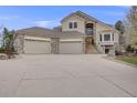 Lovely exterior elevation featuring stone accents, multi-car garage, and a large driveway at 6398 Lost Canyon Ranch Rd, Castle Rock, CO 80104