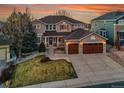 Charming two-story home with a manicured lawn and two-car garage, enhanced by a colorful dusk sky at 9845 Glenstone Trl, Highlands Ranch, CO 80130