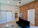 Open-concept living room with exposed brick wall, sliding barn door, and modern furniture at 2737 N Marion St, Denver, CO 80205