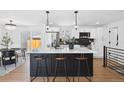 Bright kitchen features modern black and white cabinets, stainless steel appliances, and an island with bar stool seating at 290 Beryl Way, Broomfield, CO 80020
