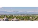 Picturesque view overlooking lush trees and rooftops with majestic snow-capped mountains in the distance at 16383 Ute Peak Way, Broomfield, CO 80023