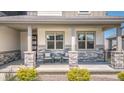 Charming front porch featuring stone pillars, comfortable seating, and manicured landscaping at 16383 Ute Peak Way, Broomfield, CO 80023