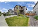 Attractive two-story house with a well-kept lawn, small trees, and rock landscaping on a sunny day at 933 Canal West Dr, Brighton, CO 80603