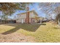 Large backyard with mature trees, green grass, brick chimney, covered patio, and wood fence at 7867 S Poplar Way, Centennial, CO 80112