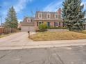 Traditional brick home with a well-maintained lawn, mature trees, and attached two-car garage at 7426 S Hudson Way, Centennial, CO 80122