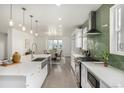 Open kitchen featuring an island with sink, white cabinets, stainless appliances and green tile backsplash at 3350 S Eudora St, Denver, CO 80222