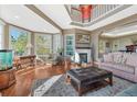 Sun-drenched living room featuring hardwood floors, fireplace, large windows, and neutral furniture at 7672 S Ensenada Ct, Centennial, CO 80016