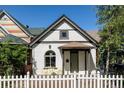 Charming home featuring a picket fence, stucco siding, and a cozy front porch sitting area at 321 Fox St, Denver, CO 80223