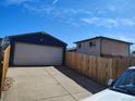 Spacious detached garage adjacent to a brick home, secured by a wooden fence at 15003 Olmsted Dr, Denver, CO 80239