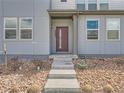 Close-up of a modern townhouse front entrance featuring desert landscaping, concrete steps, and red front door at 6492 N Ceylon St, Denver, CO 80249