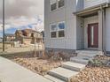 Modern townhouse front entrance with desert-style landscaping, concrete steps, and a red front door at 6492 N Ceylon St, Denver, CO 80249